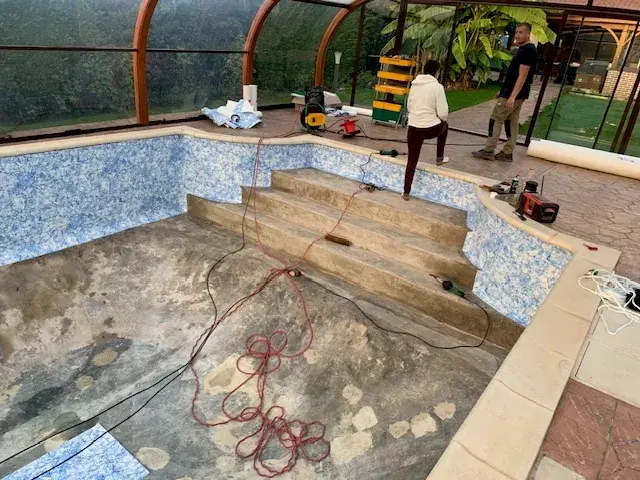 Bassin sous véranda en cours de rénovation : parois et escalier habillés, fond encore à nu